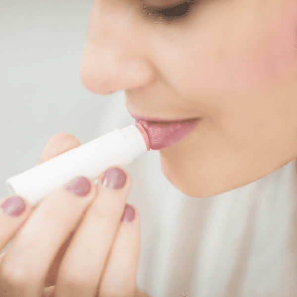 A woman applying lip balm as part of a winter sknicare routine